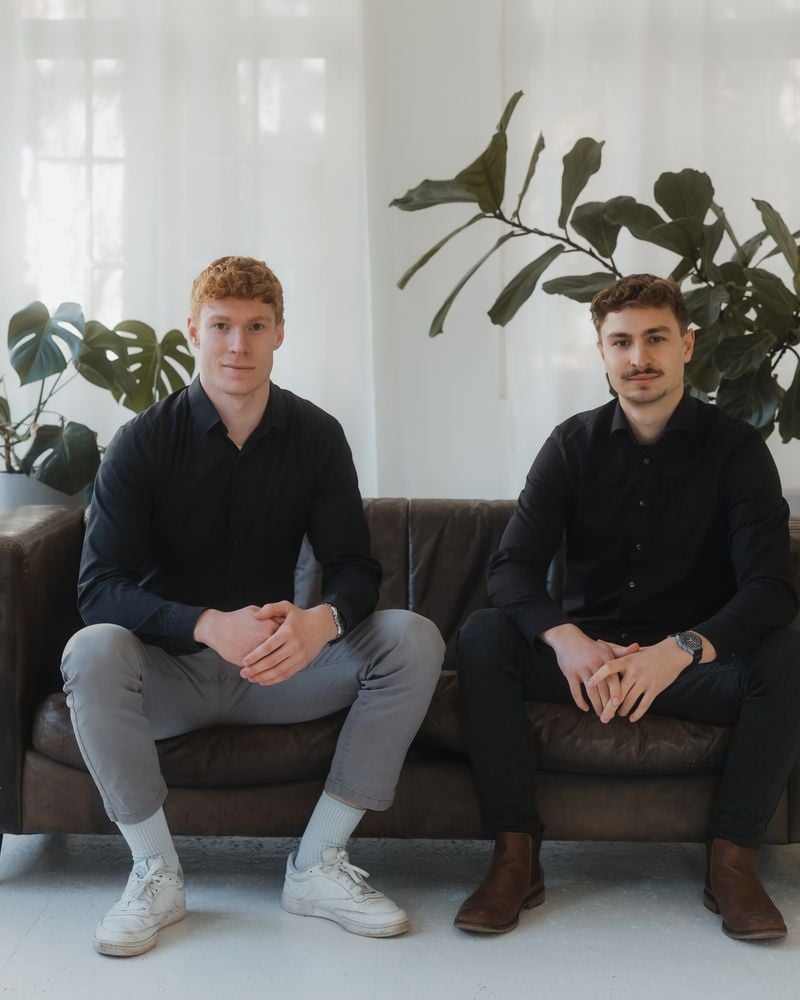 Leonard Grotz und Paul Schlümer im Studio, sitzend auf einem Sofa vor hellem Fenster